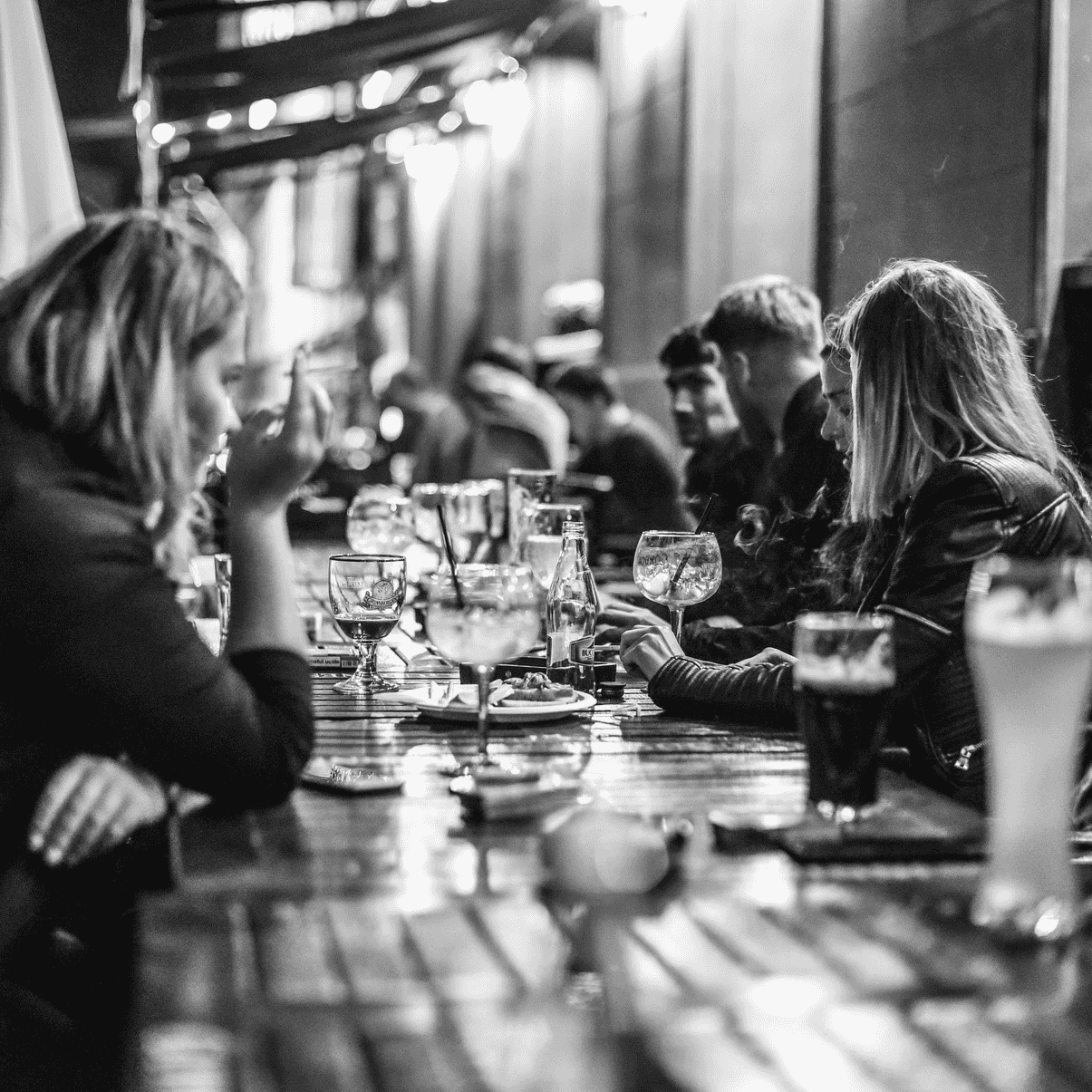 Black and white photo from revo.js 2019 After Party, showing participants sitting at the table and talking